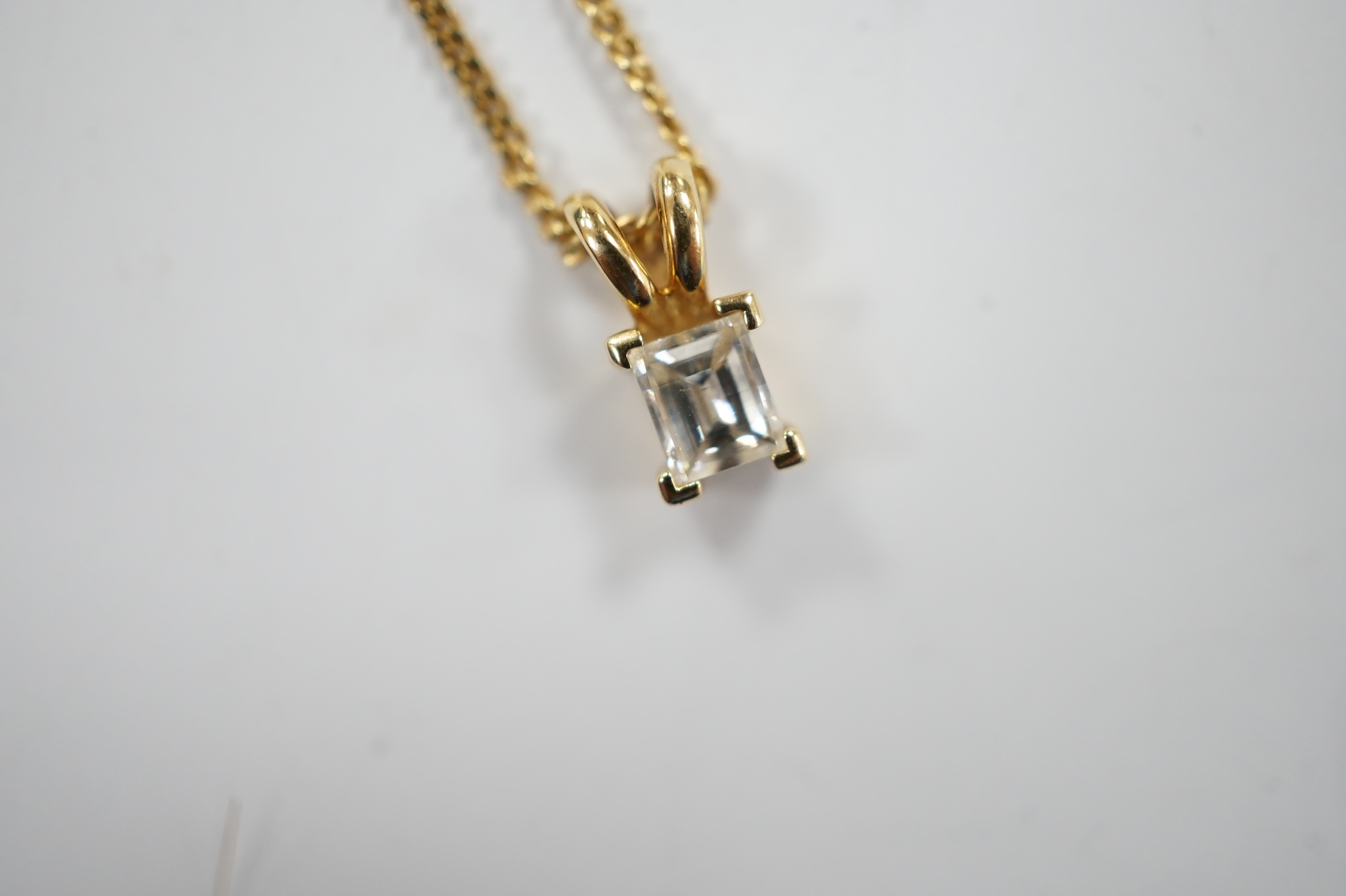 A modern 18ct gold and single stone fancy rectangular cut diamond set pendant, 9mm, on an 18ct gold fine link chain, 46cm, gross weight 3.6 grams.